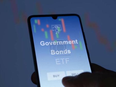 Photo for An investor analyzing the government bonds etf fund on a screen. A phone shows the prices of Government Bonds - Royalty Free Image