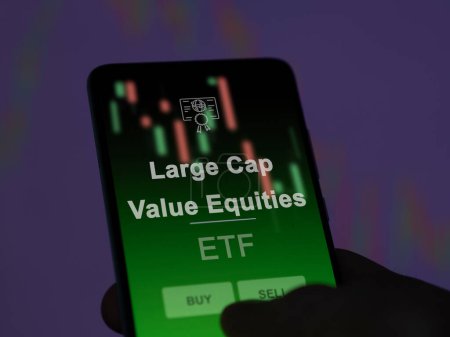An investor analyzing the large cap value equities etf fund on a screen. A phone shows the prices of Large Cap Value Equities