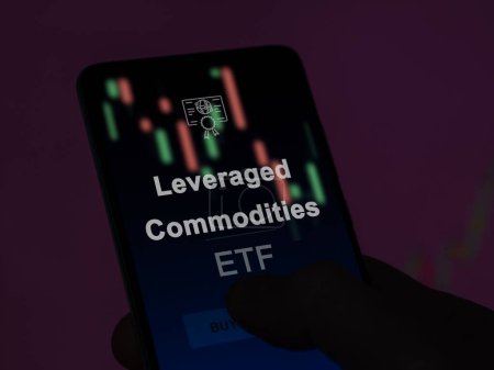An investor analyzing the leveraged commodities etf fund on a screen. A phone shows the prices of Leveraged Commodities