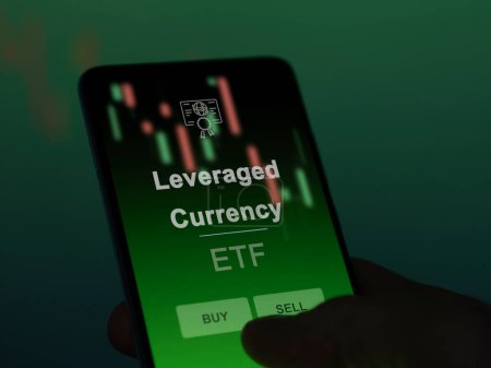 An investor analyzing the leveraged currency etf fund on a screen. A phone shows the prices of Leveraged Currency