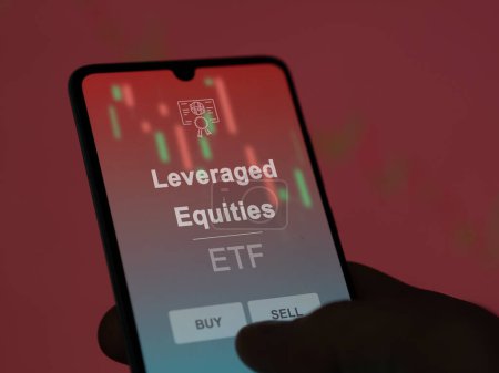An investor analyzing the leveraged equities etf fund on a screen. A phone shows the prices of Leveraged Equities
