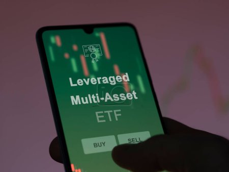An investor analyzing the leveraged multi-asset etf fund on a screen. A phone shows the prices of Leveraged Multi-Asset
