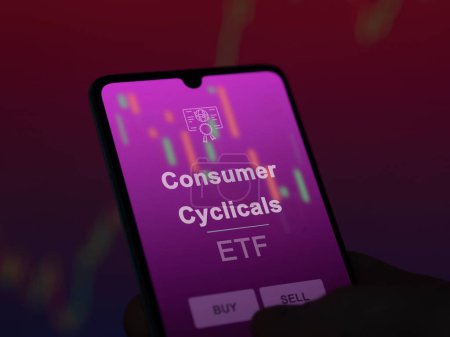 Foto de Un inversor analizando los cíclicos de consumo etf fondo en una pantalla. Un teléfono muestra los precios de los cíclicos de consumo - Imagen libre de derechos