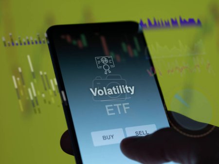 Un inversor analizando el fondo etf volatilidad en una pantalla. Un teléfono muestra los precios de la volatilidad
