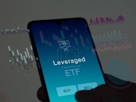 An investor analyzing the leveraged etf fund on a screen. A phone shows the prices of Leveraged