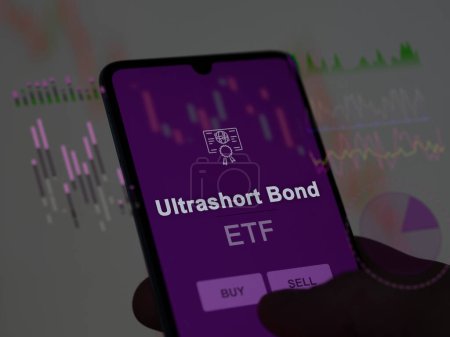 Téléchargez les photos : Un investisseur analysant le fonds d'obligations à ultrasons etf sur un écran. Un téléphone montre les prix de l'Ultrashort Bond - en image libre de droit