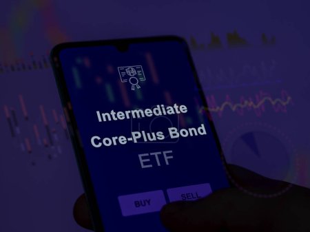 Un inversor analizando el fondo de bonos intermedios core-plus etf en una pantalla. Un teléfono muestra los precios de los bonos Core-Plus intermedios