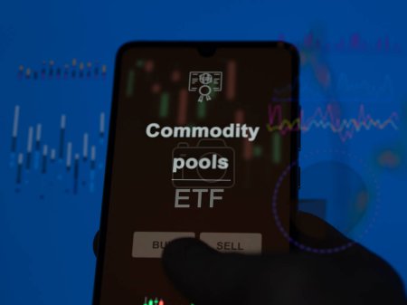 An investor analyzing the commodity pools etf fund on a screen. A phone shows the prices of Commodity pools