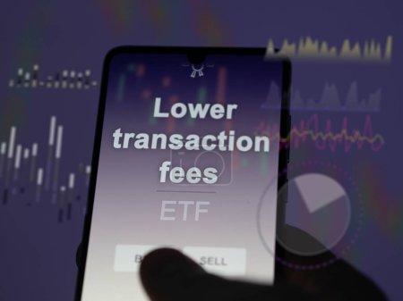 An investor analyzing the lower transaction fees etf fund on a screen. A phone shows the prices of Lower transaction fees