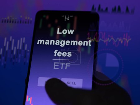 An investor analyzing the low management fees etf fund on a screen. A phone shows the prices of Low management fees