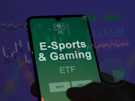 Téléchargez les photos : Un investisseur analysant le fonds e-sports & gaming etf sur un écran. Un téléphone affiche les prix de E-Sports & Gaming - en image libre de droit