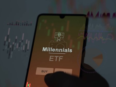 An investor analyzing the millennials etf fund on a screen. A phone shows the prices of Millennials