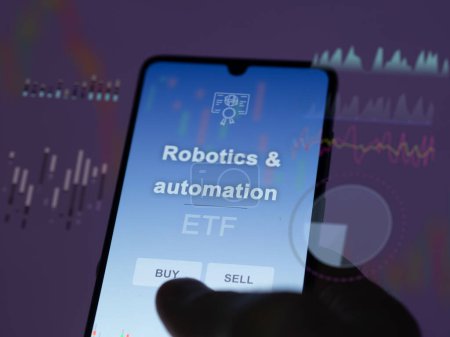 Un inversor que analiza el fondo etf de robótica y automatización en una pantalla. Un teléfono muestra los precios de Robótica y automatización