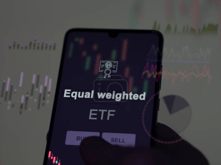 An investor analyzing the equal weighted etf fund on a screen. A phone shows the prices of Equal weighted