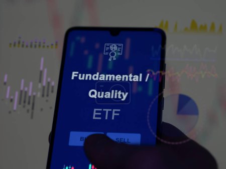 Un inversor que analiza el fondo etf fundamental / de calidad en una pantalla. Un teléfono muestra los precios de Fundamental / Calidad