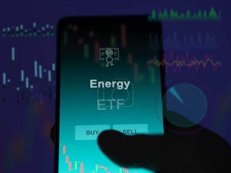 Ein Investor analysiert den Energiefonds auf einem Bildschirm. Ein Telefon zeigt die Energiepreise an