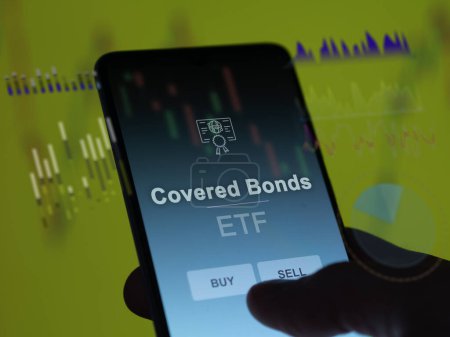 An investor analyzing the covered bonds etf fund on a screen. A phone shows the prices of Covered Bonds