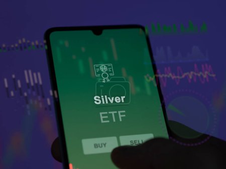 An investor analyzing the silver etf fund on a screen. A phone shows the prices of Silver