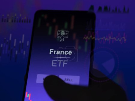 An investor analyzing the france etf fund on a screen. A phone shows the prices of France
