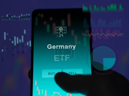 Téléchargez les photos : Un investisseur analyse le fonds germany etf sur un écran. Un téléphone montre les prix de l'Allemagne - en image libre de droit