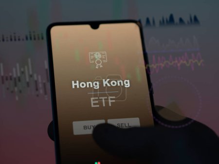 Téléchargez les photos : Un investisseur analysant le fonds hong kong etf sur un écran. Un téléphone montre les prix de Hong Kong - en image libre de droit