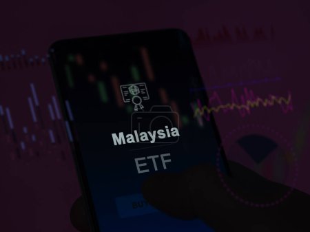 Téléchargez les photos : Un investisseur analysant le fonds malaysia etf sur un écran. Un téléphone montre les prix de la Malaisie - en image libre de droit