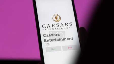 Photo for April 04th 2024. The logo of Caesars Entertainment on the screen of an exchange. Caesars Entertainment price stocks, $CZR on a device. - Royalty Free Image