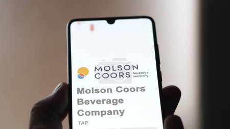 Photo for April 04th 2024. The logo of Molson Coors Beverage Company on the screen of an exchange. Molson Coors Beverage Company price stocks, $TAP on a device. - Royalty Free Image
