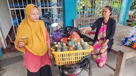 Téléchargez les photos : Pinrang Indonesia, 21 July 2023: A female herbal medicine seller, serving customers in front of the house in the morning in the village of Masolo Pinrang, Indonesia - en image libre de droit