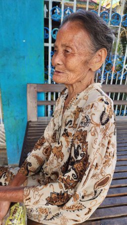 Téléchargez les photos : Pinrang Indonésie, 28 juillet 2023 : Une vieille mère le matin assise détendue dans une salle au visage étonné et choqué en posant pour la caméra, dans le village de Masolo Pinrang Indonésie - en image libre de droit