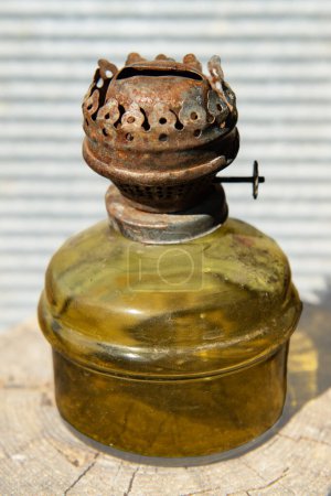 Foto de Una vieja y sucia lámpara de queroseno hecha de vidrio verde claro está sobre una tabla de madera - Imagen libre de derechos