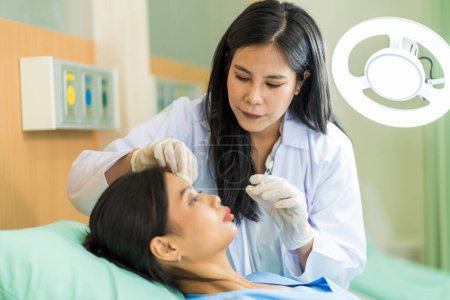 Foto de Mujer asiática consultando sobre cirujano cosmético y hacer inyecciones de Botox en la cara para procedimientos de belleza. Cirugía plástica frente a la mujer - Imagen libre de derechos