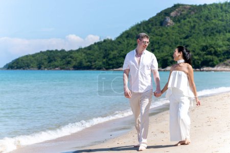Photo for A couple of men and women of different nationalities go to the beach and walk happily on the beach together. on summer vacation - Royalty Free Image
