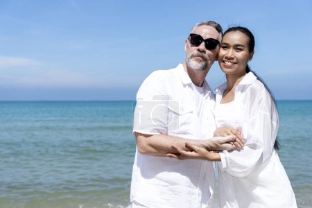 Téléchargez les photos : Un couple d'hommes et de femmes de différentes nationalités vont à la plage et marchent heureux sur la plage ensemble. en vacances d'été - en image libre de droit
