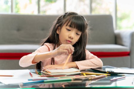 Photo for Asian girl doing her own homework at home - Royalty Free Image