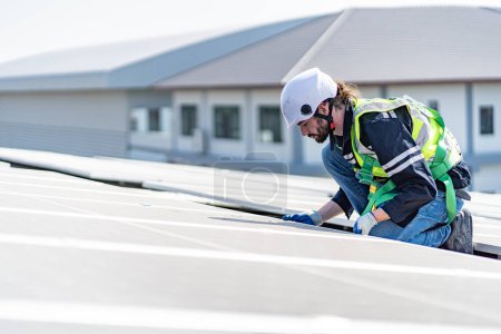 Téléchargez les photos : Male engineer installing or checking the working condition of solar panels on the roof or at the height of the factory for saving electricity was broken to use renewable energy from the sun - en image libre de droit