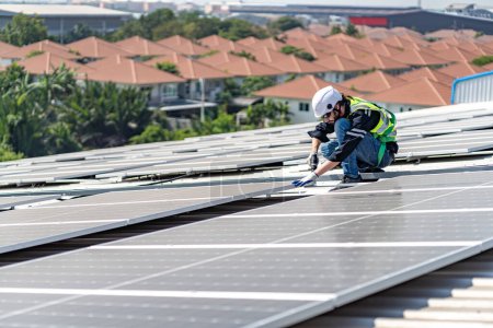 Foto de Male engineer installing or checking the working condition of solar panels on the roof or at the height of the factory for saving electricity was broken to use renewable energy from the sun - Imagen libre de derechos