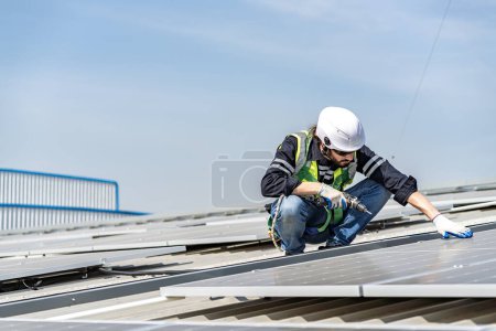 Téléchargez les photos : Male engineer installing or checking the working condition of solar panels on the roof or at the height of the factory for saving electricity was broken to use renewable energy from the sun - en image libre de droit