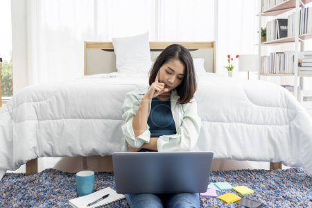 Foto de Asian woman working at bedside in bedroom at home with her tablet - Imagen libre de derechos