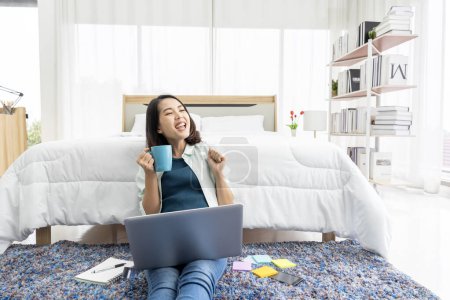 Téléchargez les photos : Asian woman working at bedside in bedroom at home with her tablet - en image libre de droit