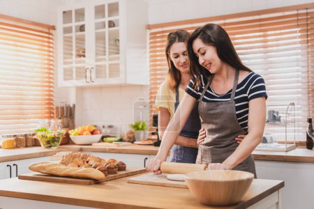 Foto de Female and female or LGBT couples are happily cooking bread together in the home kitchen. - Imagen libre de derechos