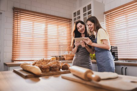 Téléchargez les photos : Female and female or LGBT couples are happily cooking bread together in the home kitchen. - en image libre de droit