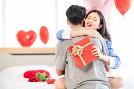 Foto de Asian couple Showing love surprise giving flowers or gifts to each other on important occasions such Valentine's Day birthdays or wedding anniversaries with love and warmth in bedroom of their home - Imagen libre de derechos