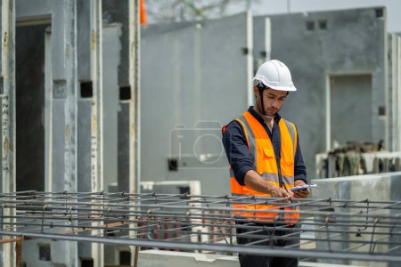 Foto de Los ingenieros masculinos están inspeccionando y controlando el trabajo de los empleados y la calidad de los productos manufacturados para cumplir con los estándares. En fábricas industriales que producen paredes prefabricadas prefabricadas - Imagen libre de derechos