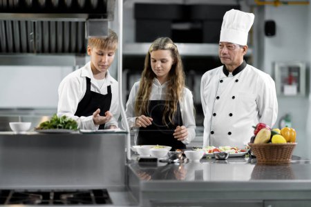Foto de Los estudiantes están aprendiendo a cocinar en un instituto culinario con una cocina estándar y equipo completo. Y tener un chef profesional como entrenador. - Imagen libre de derechos