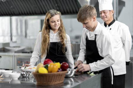 Téléchargez les photos : Les étudiants apprennent à cuisiner dans un institut culinaire avec une cuisine standard et un équipement complet. Et avoir un chef professionnel comme formateur. - en image libre de droit