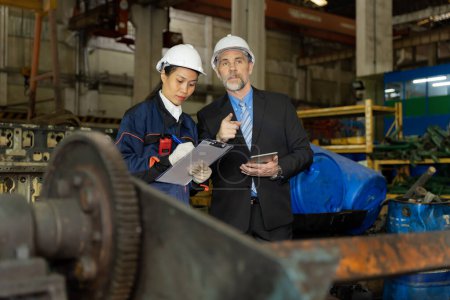 Téléchargez les photos : Un homme d'affaires inspecte le travail d'un travailleur sur place dans une ancienne usine pour la répétition des moteurs de train. - en image libre de droit