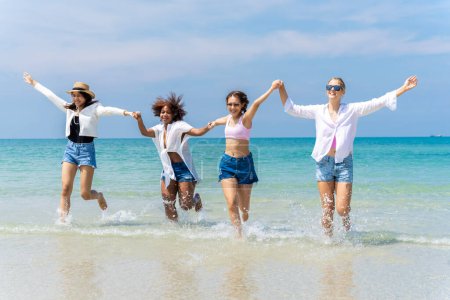 Téléchargez les photos : Photo d'un groupe de filles de différentes ethnies courant et s'amusant ensemble à la plage. un jour frais - en image libre de droit