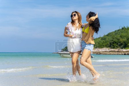Téléchargez les photos : LGBTQ lesbian couple on the beach The couple went to the sea on vacation together happily. - en image libre de droit