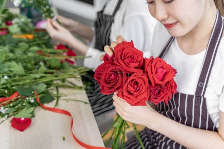 Téléchargez les photos : Groupe de fleuristes asiatiques femmes organisent des fleurs pour les clients qui viennent les commander pour diverses cérémonies telles que les mariages, la Saint-Valentin ou pour donner à des êtres chers. - en image libre de droit